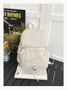 Detail of off-white backpack featuring bungee cord design and front zipper pocket