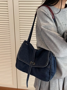 Retro denim shoulder bag in dark blue with contrast red leather strap and metal buckle
