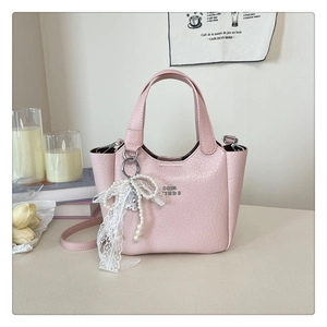 Pink faux leather tote bag with crocodile texture and lace pearl charm on soft background