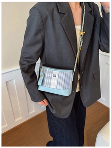 Détail du sac à bandoulière rayé bleu clair avec sphère dorée et bandoulière chaîne