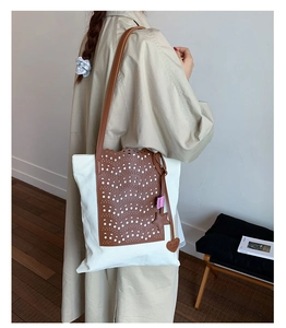 Detail of laser-cut wave pattern on a canvas tote bag with stylish leather hanging charms