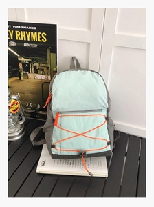 Close-up of mint green and grey nylon sports backpack with bright orange drawstring details