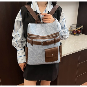 Close-up of blue denim backpack with brown leather straps and metal hardware