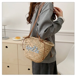 Détail du sac de plage en paille avec broderie Hello bleu clair et anses en cuir marron