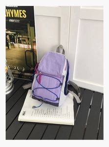 Detail of light purple nylon backpack with blue bungee cord on a stylish desktop