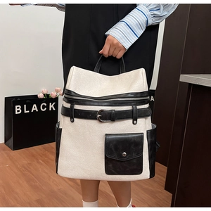 Detailed view of cream and black leather backpack featuring buckle strap and front pocket