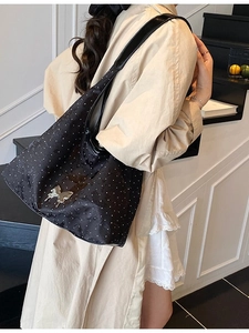 Sac fourre-tout noir à pois pour femme avec boucle papillon argentée porté épaule