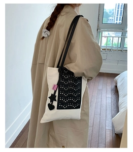 Detail of canvas tote bag with laser-cut black panel and star-heart charms