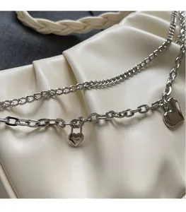 Vue détaillée du pendentif coeur argenté avec double chaîne sur texture plissée
