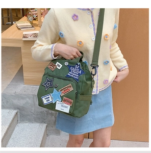Detail eines armee grünen Canvas-Rucksacks mit Vintage-Patches und Stickerei vorne