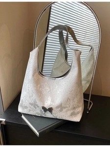 Sac à bandoulière blanc jacquard papillon avec boucle en métal reflété dans un miroir