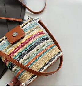 Détail d'un sac en paille tressée colorée avec rabat en cuir brun et boucle argent