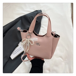 Detailed macro view of pink crocodile textured bucket bag with pearl lace bow charm