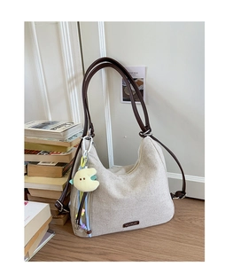 Close-up of beige canvas shoulder bag with brown leather straps and moon plush charm