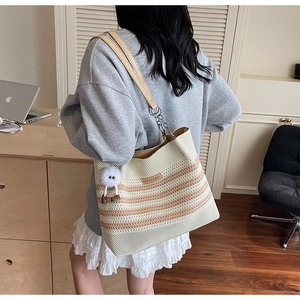 Détail du sac de plage en tricot avec rayures, anses en cuir et chaîne et pompon