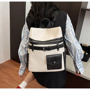 Modern white backpack with black leather accents shown on a model in a minimalist room