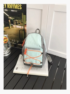 Detail of mint green lightweight nylon outdoor backpack with orange bungee cord system