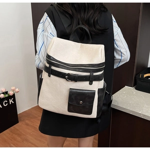 Detailed view of bicolor leather backpack showing side pockets and belt buckle accents