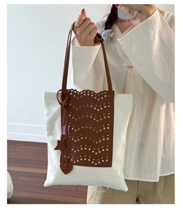 Detail of canvas bucket bag with brown laser-cut wave pattern and leather charms