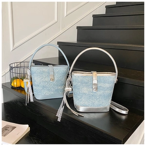 Dettaglio di borse a secchiello in denim con nappe in pizzo su scale nere in casa chic