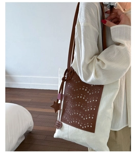 Close-up of hollowed-out leather texture on a white canvas bucket bag with heart charm