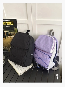 Detailed view of lightweight nylon backpacks with criss-cross elastic cords on camping table