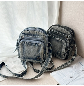 Gros plan détaillé du sac à bandoulière en denim rétro avec logo M en métal et multi-zips
