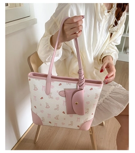 Close-up of a white tote bag featuring pink rabbit prints and a matching small pouch