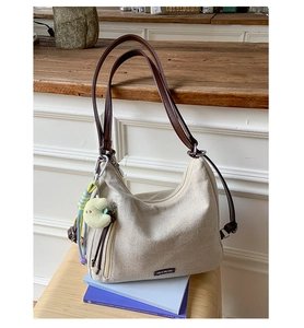 Detail view of canvas tote bag with brown leather straps and yellow moon plush charm