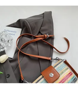 Gros plan d'un sac en paille tissé coloré avec bandoulière en cuir brun et boucle métal