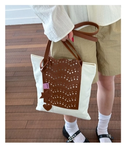 Detail of color-block tote bag with laser-cut leather and star charms on model