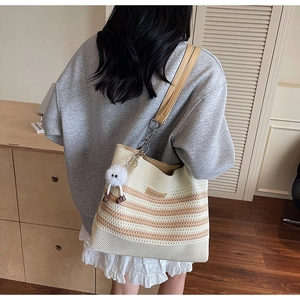 Détail d'un grand sac cabas en maille rayée avec chaîne et breloque pelucheuse