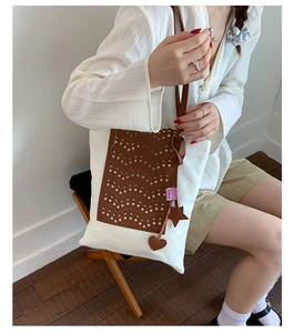 Detail of canvas tote bag with laser-cut leather pocket and heart-shaped charms