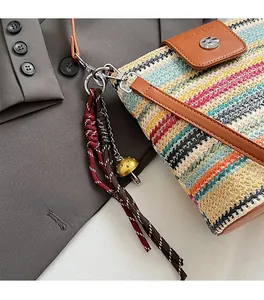Détail du sac seau en paille tissé avec rabat en cuir marron et pendentif bohème