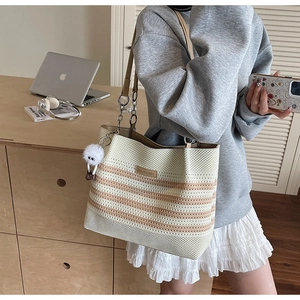 Détail du sac de plage en tricot avec bandoulière en cuir et breloque en peluche douce
