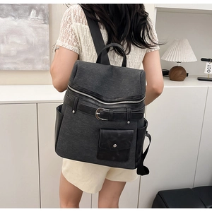 Detail of grey canvas and black leather patchwork backpack with silver metal buckle strap
