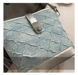 Dettaglio della borsa a secchiello in denim azzurro con pieghe e chiusura a scatto argento