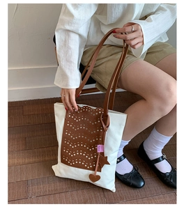 Detail showing laser-cut wave leather pattern and star heart charms on canvas tote