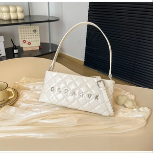 Detail of white quilted crossbody bag with golden CLEAROK logo and metal heart charm