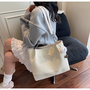 Détail du sac cabas au crochet crème avec écusson en cuir et bandoulière en chaîne