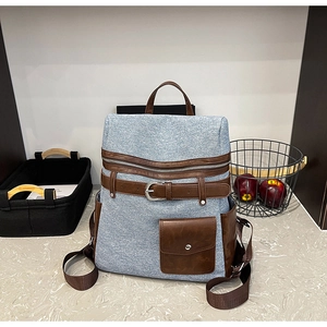 Close-up of retro denim and brown leather stitching with belt buckle detail on backpack