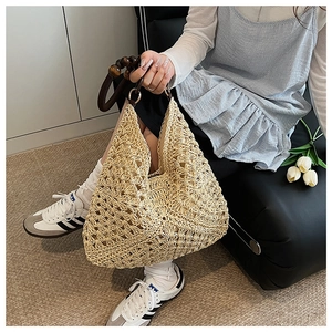 Close-up of beige woven straw tote bag featuring decorative dark brown wooden beads