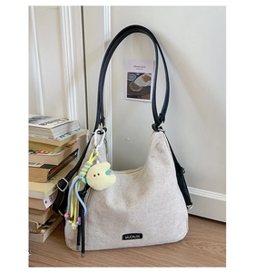 Detail of a minimalist canvas crescent hobo bag with moon charm on wooden surface