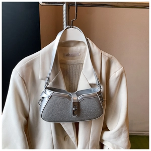 Close-up of a silver shimmering shoulder bag with metallic buckle on a blazer background