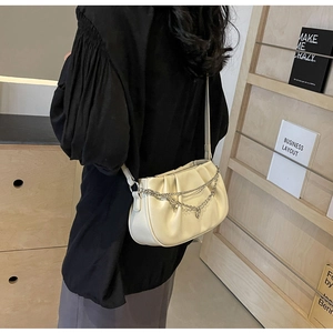 Sac nuage plissé beige chic avec double chaîne en métal porté par un mannequin