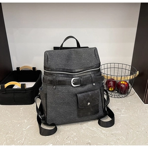 Close-up of textured grey canvas backpack with black leather straps and silver buckles