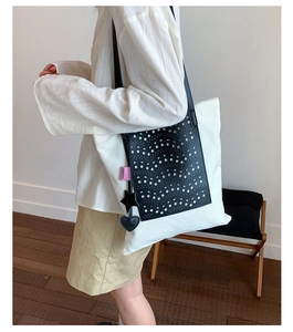 Detail view of large tote bag with laser-cut leather texture and star heart charms