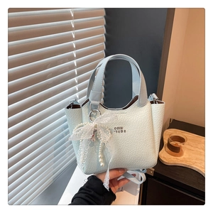 Detailed close-up of light mint bucket bag featuring a white lace pearl bow charm