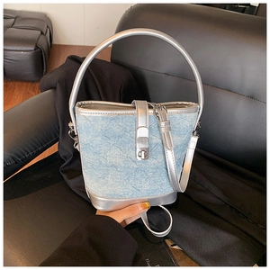 Dettaglio della borsa a secchiello in denim azzurro con manici argentati e fibbia