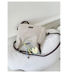 Detail of canvas tote bag with brown leather straps and cute yellow duck charm decoration